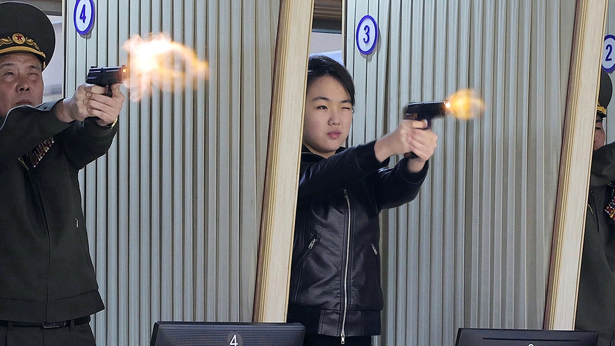 Kim Jong Un's daughter, center, tries out a new pistol at a factory producing pistols