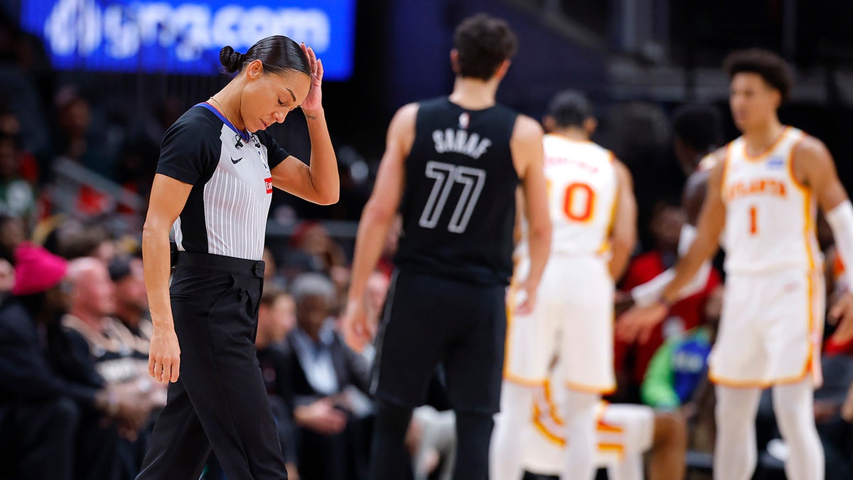 Referee Sha'Rae Mitchell holding her head after a collision during a basketball game at State Farm Arena