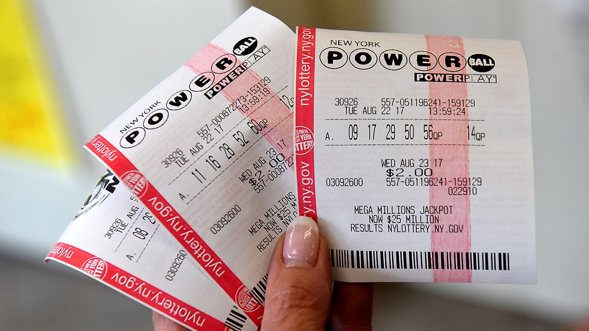 A woman holding 3 New York Powerball tickets.