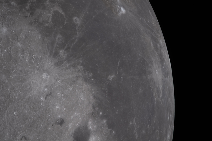 Flat gray moon terrain is punctuated by bright craters surrounded by rays
