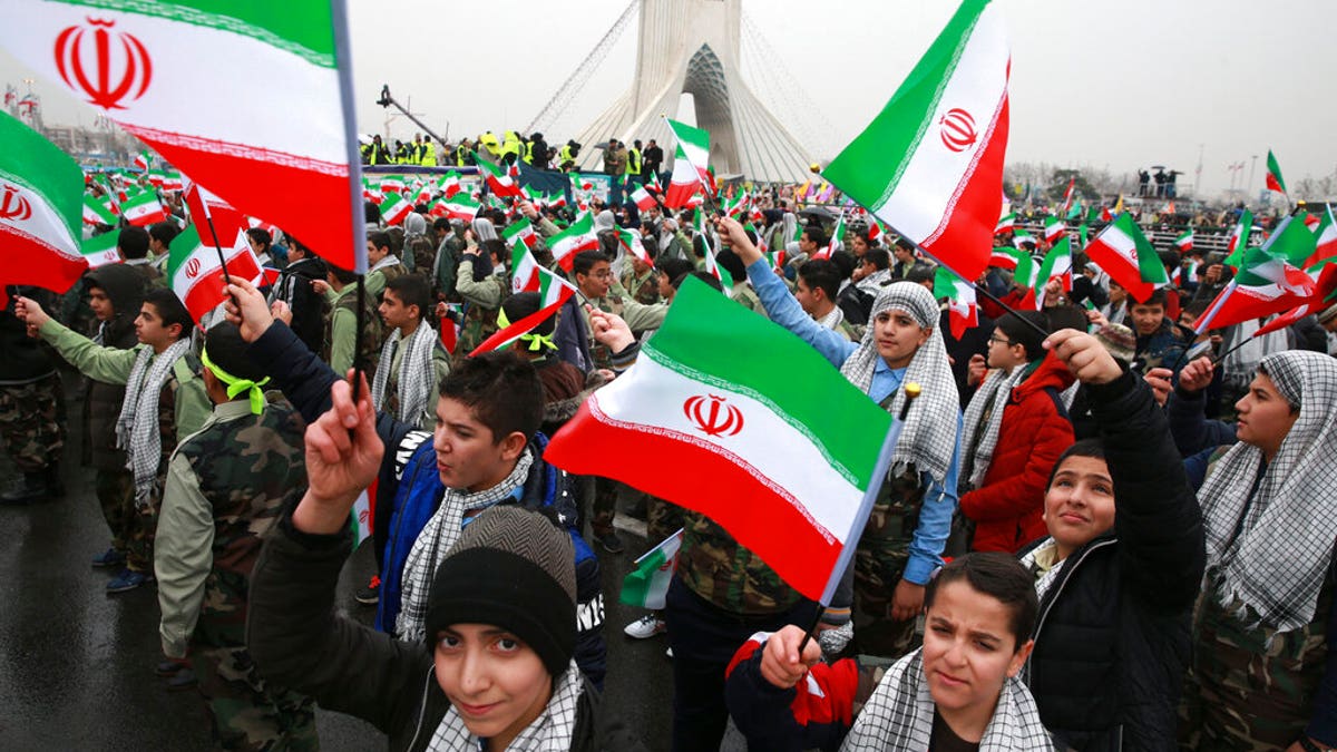 Children waving Iranian flags during a ceremony at Azadi Square in Tehran