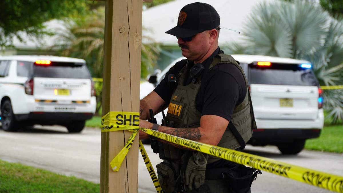 A man wearing a black shirt and blue jeans standing on a sidewalk