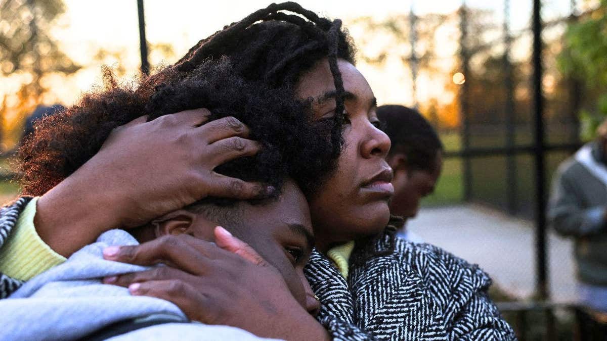 A mother holds her son close during a vigil for deceased Jaden Pierre