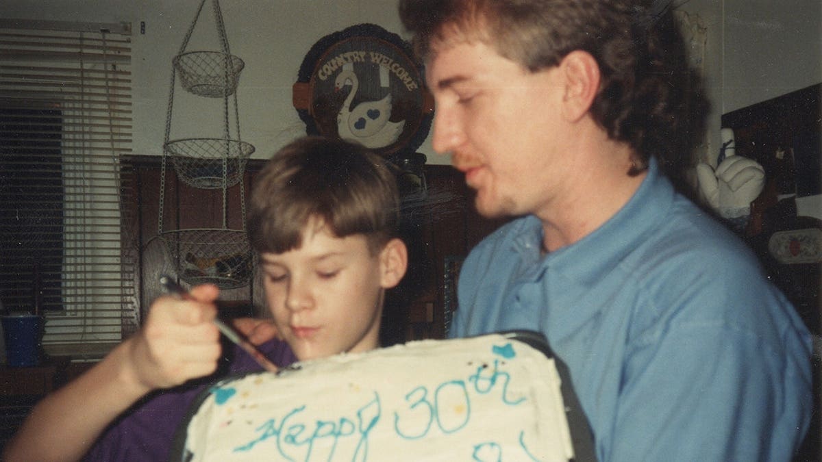 Timothy Jones Sr. holding Timothy Jones Jr. who is cutting a birthday cake.