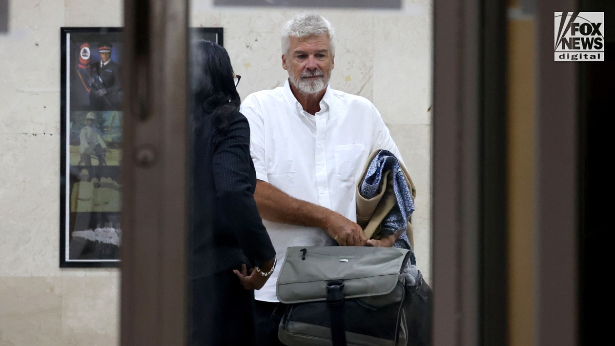 Brian Hooker leaves police station in The Bahamas, with lawyer.