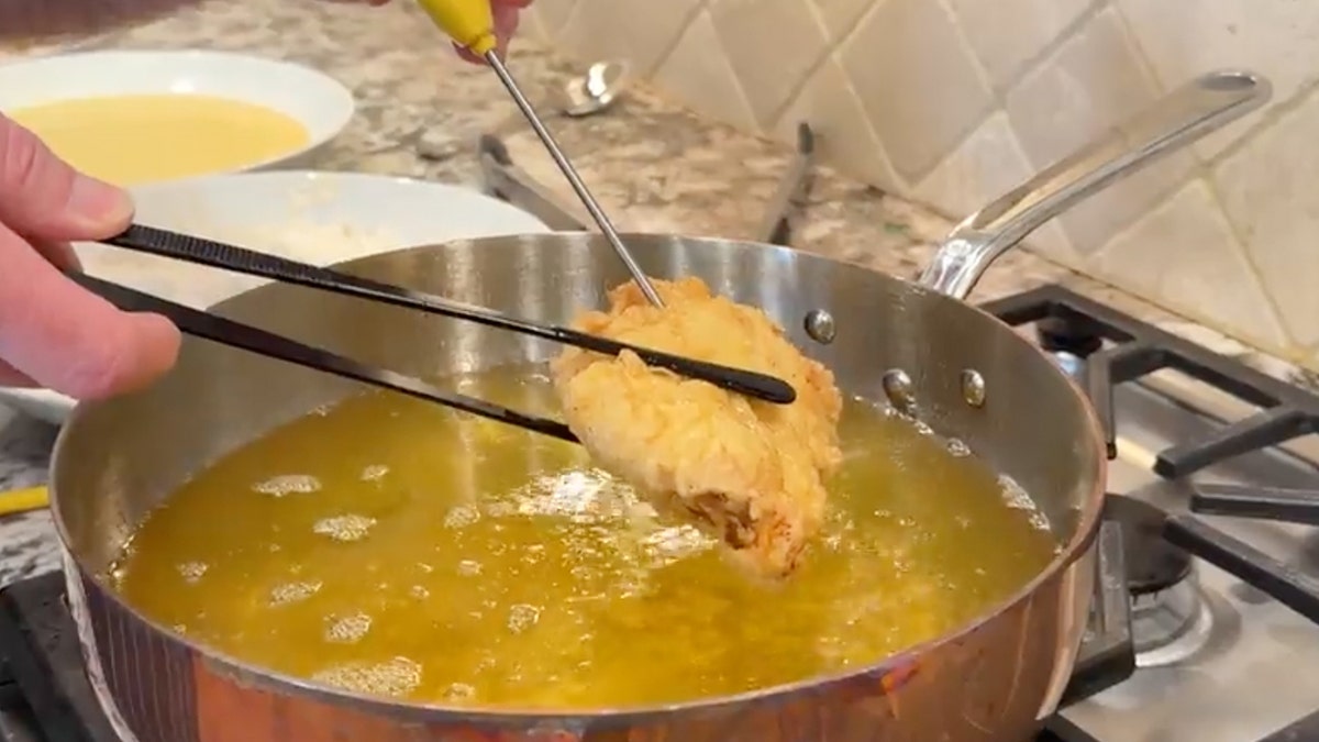 Walker taking fried chicken fillet out of pot