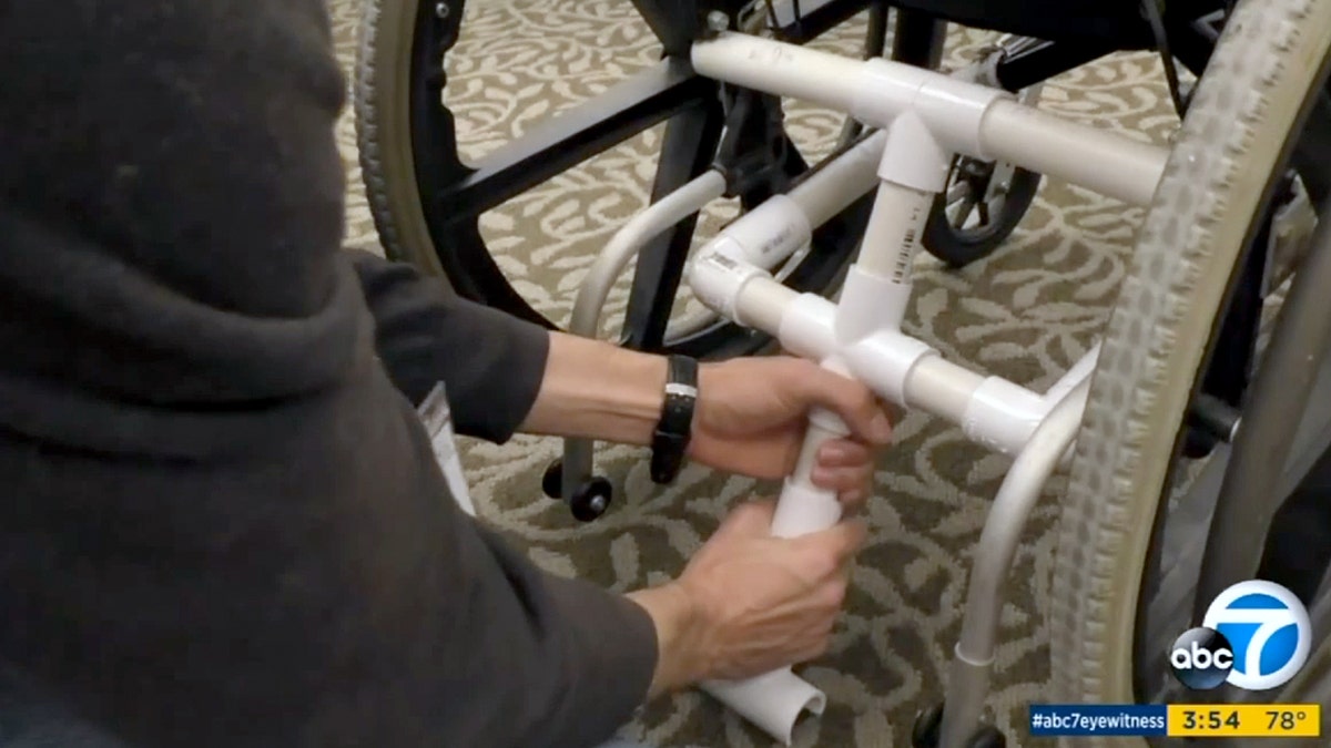 A PVC pipe contraption is attached to a wheelchair.