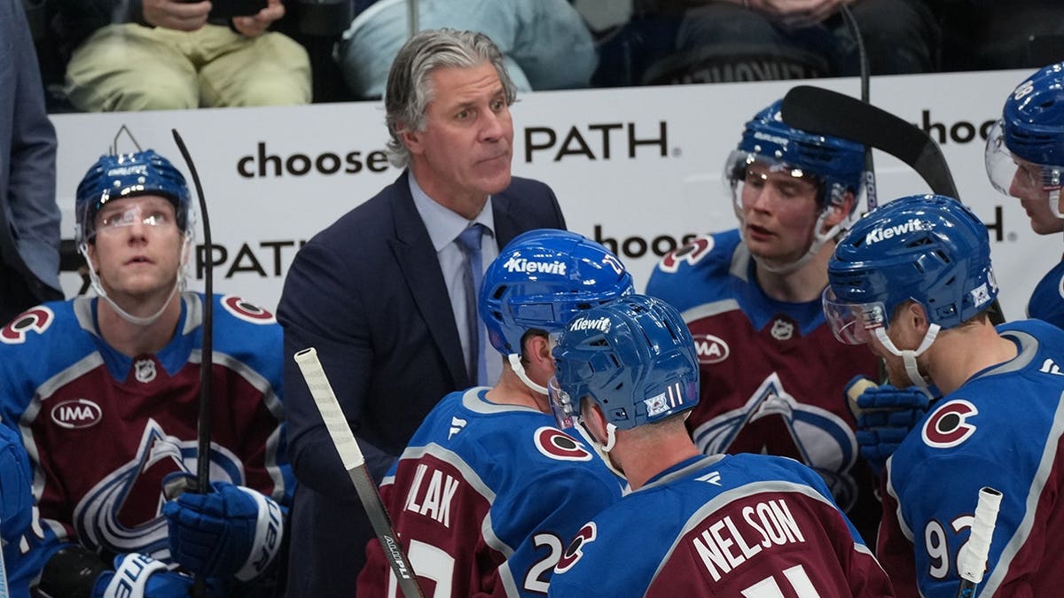 Colorado Avalanche head coach Jared Bednar confers with players during a timeout on the ice.