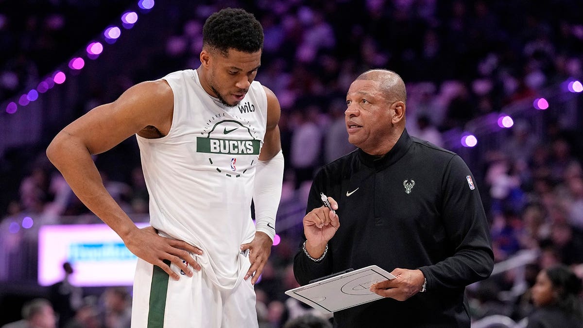Giannis Antetokounmpo and head coach Doc Rivers talking courtside