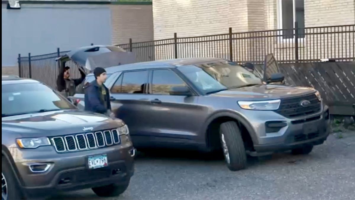 Police officers standing between two cars