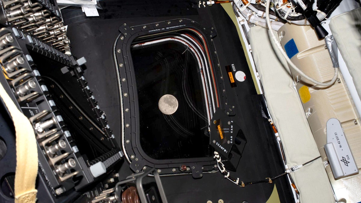 Artemis II crew viewing the Moon through the Orion spacecraft window.