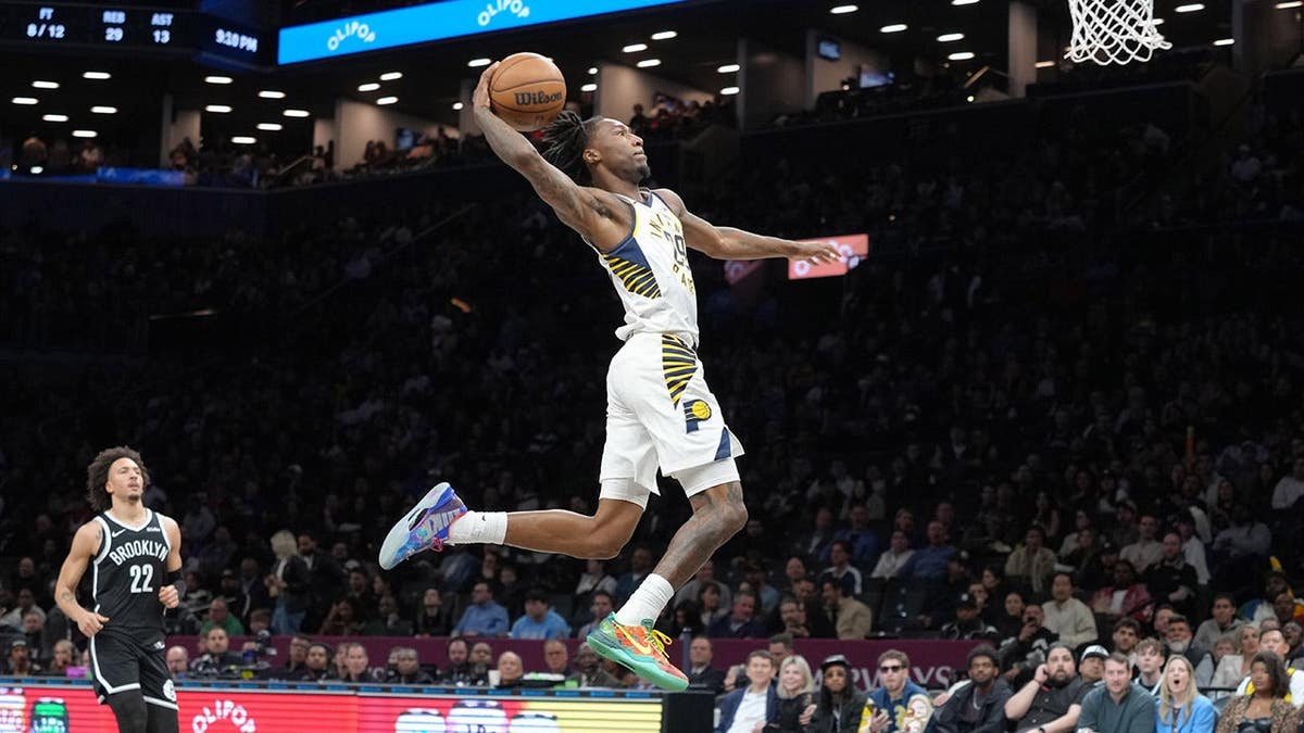 Indiana Pacers guard Quenton Jackson leaping to dunk the ball against Brooklyn Nets forward Jalen Wilson at Barclays Center.