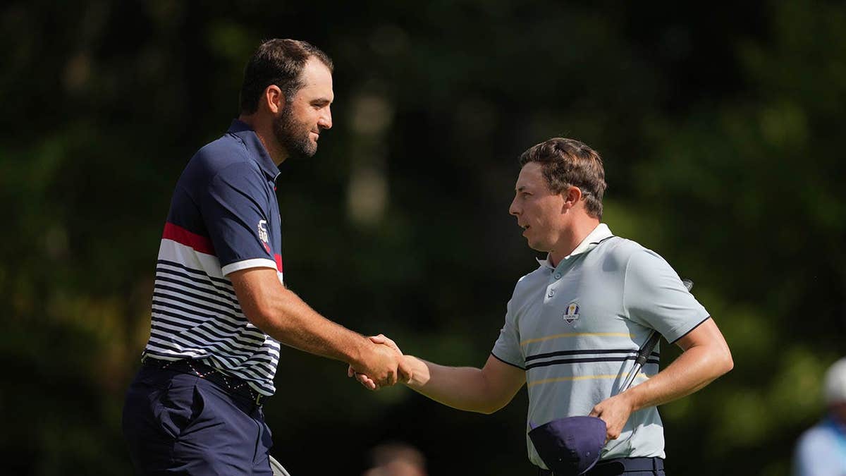 Scottie Scheffler and Matt Fitzpatrick shaking hands on the 15th green at Bethpage State Park Golf Course.