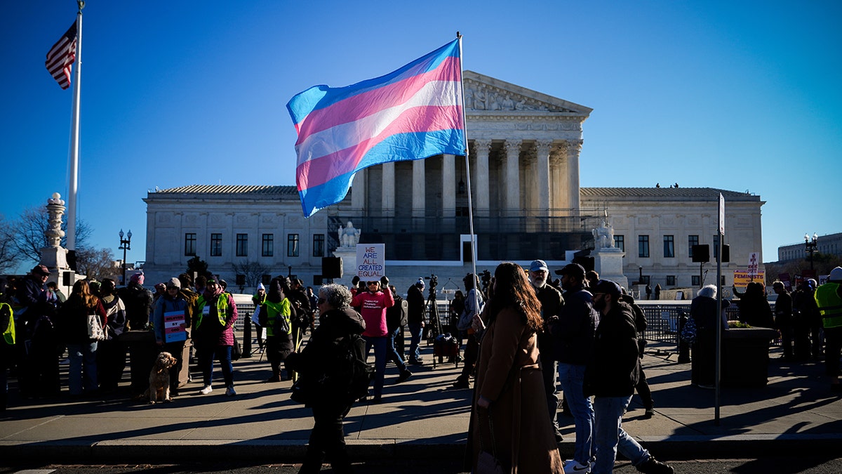 Protester carrying transgender pride flag outside Supreme Court building in Washington