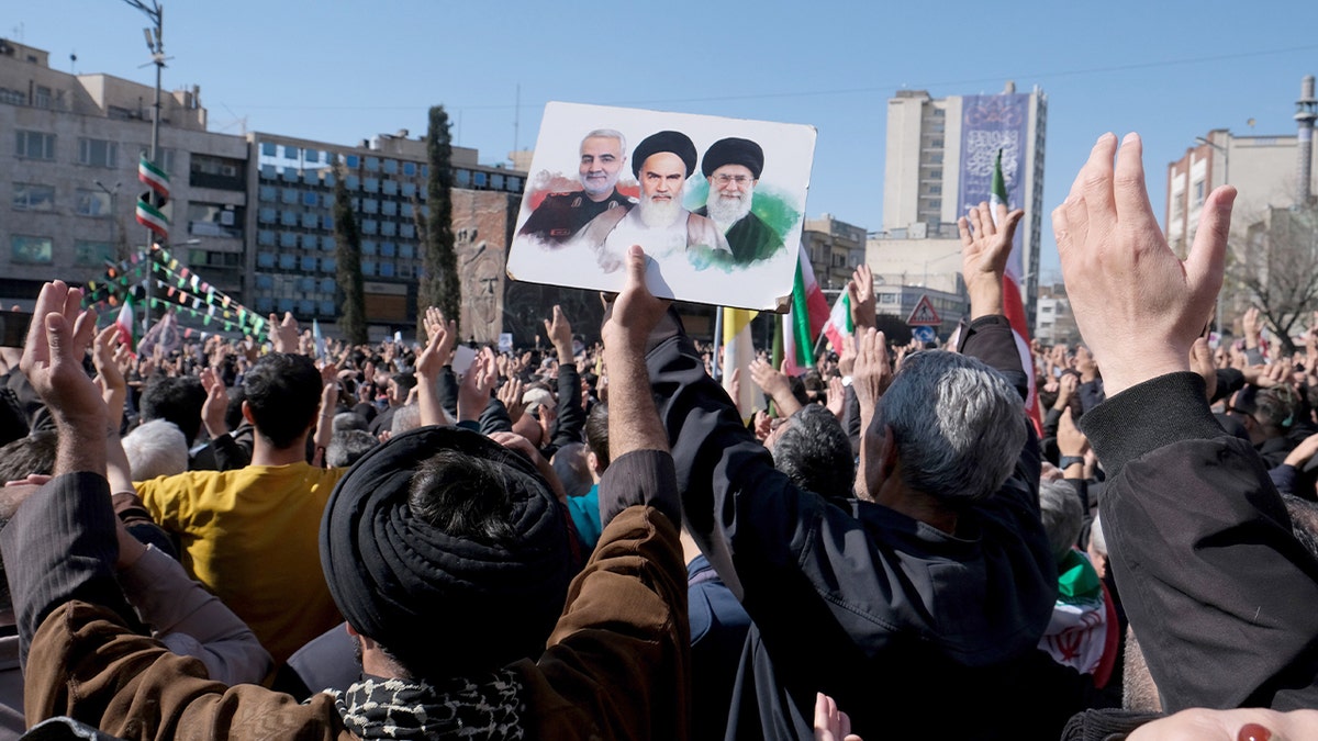 Crowds assemble in Tehran’s Revolution Square holding images of Ayatollah Ali Khamenei, Qassem Soleimani and Ayatollah Ruhollah Khomeini beneath a large banner.