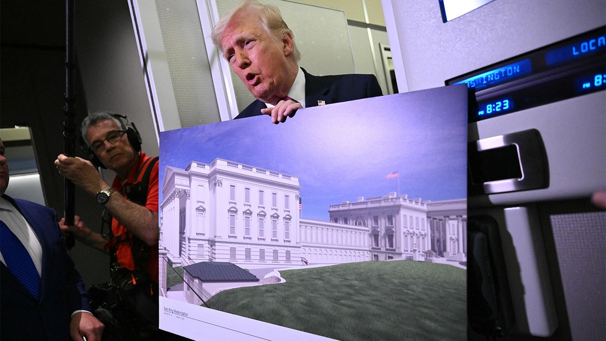 President Donald Trump holding a rendering of the East Wing modernization aboard Air Force One