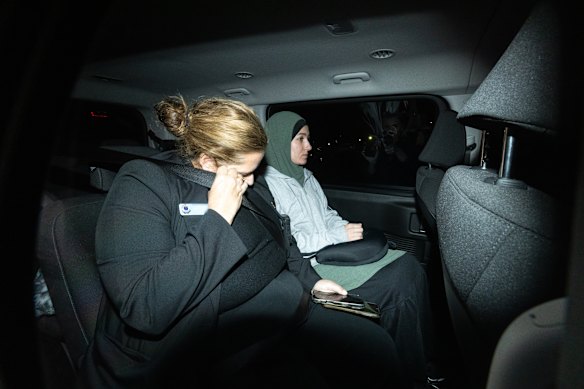 Janai Safar is escorted from the airport to the police station.