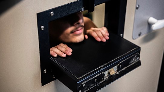 A Silverwater Correctional Centre prisoner looks out the meal slot of his cell door.