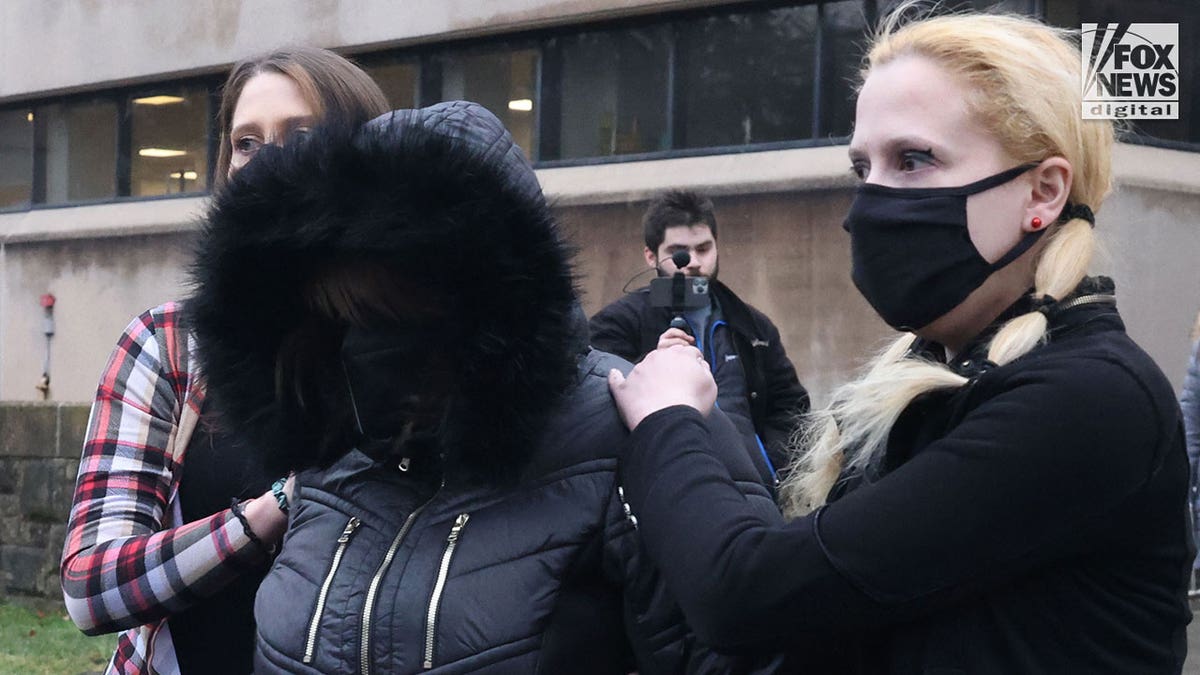Maryann Kohberger wearing black coat with fur-lined hood is helped to car by two younger women outside Monroe County Court House