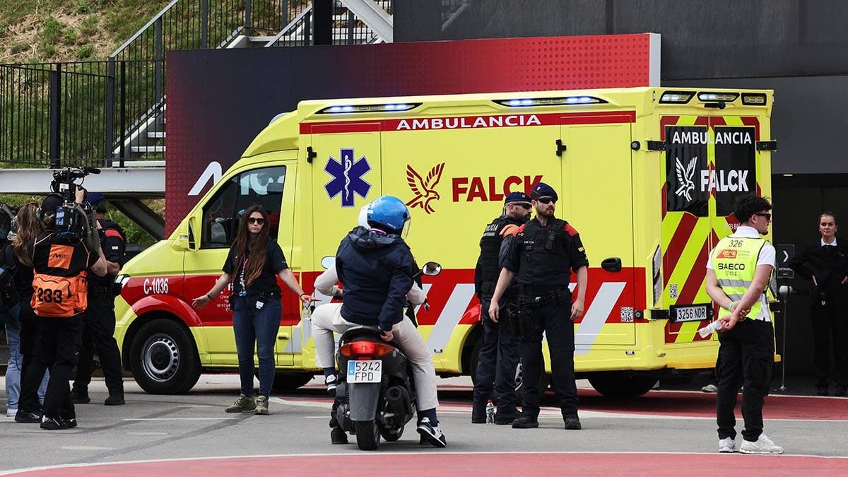 Alex Marquez sitting on the ground with an ambulance arriving at the race track