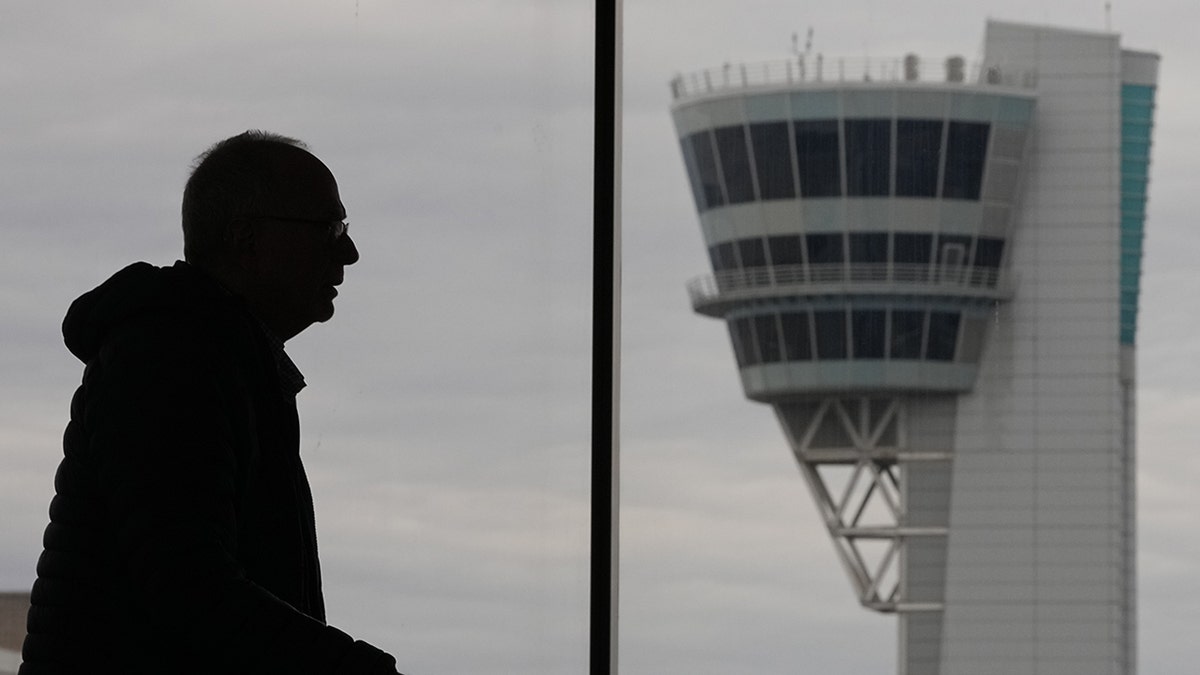 A traveler walking near an air traffic control tower at Philadelphia International Airport