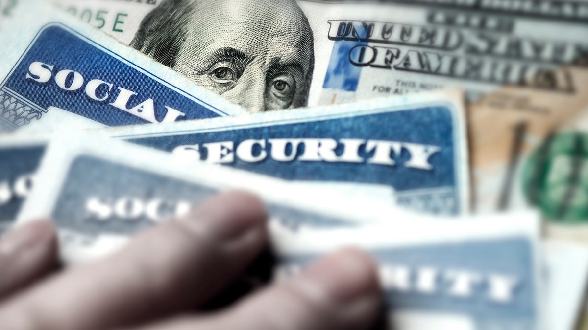 Several Social Security cards placed on a $100 bill.