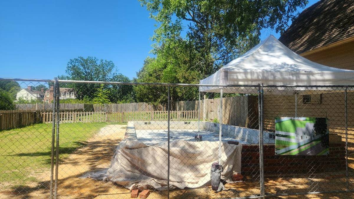 A metal fence is set in front of a yard with a pop-up tent.