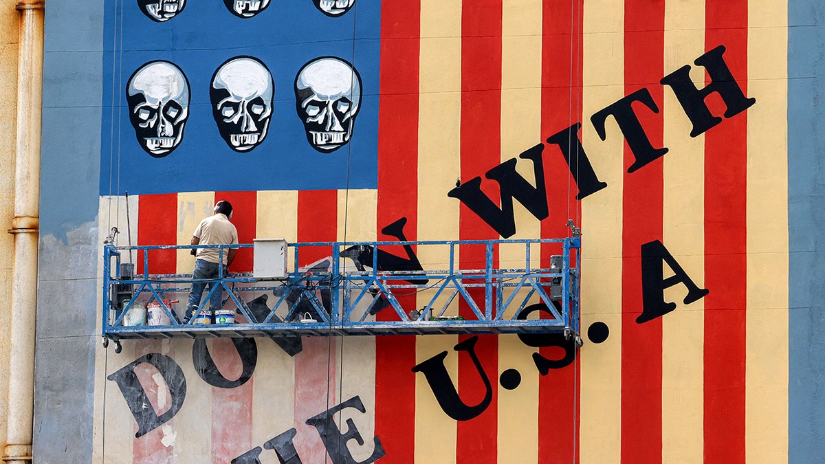 A man painting an anti-US mural on a building wall on Karim Khan Zand Avenue in Tehran