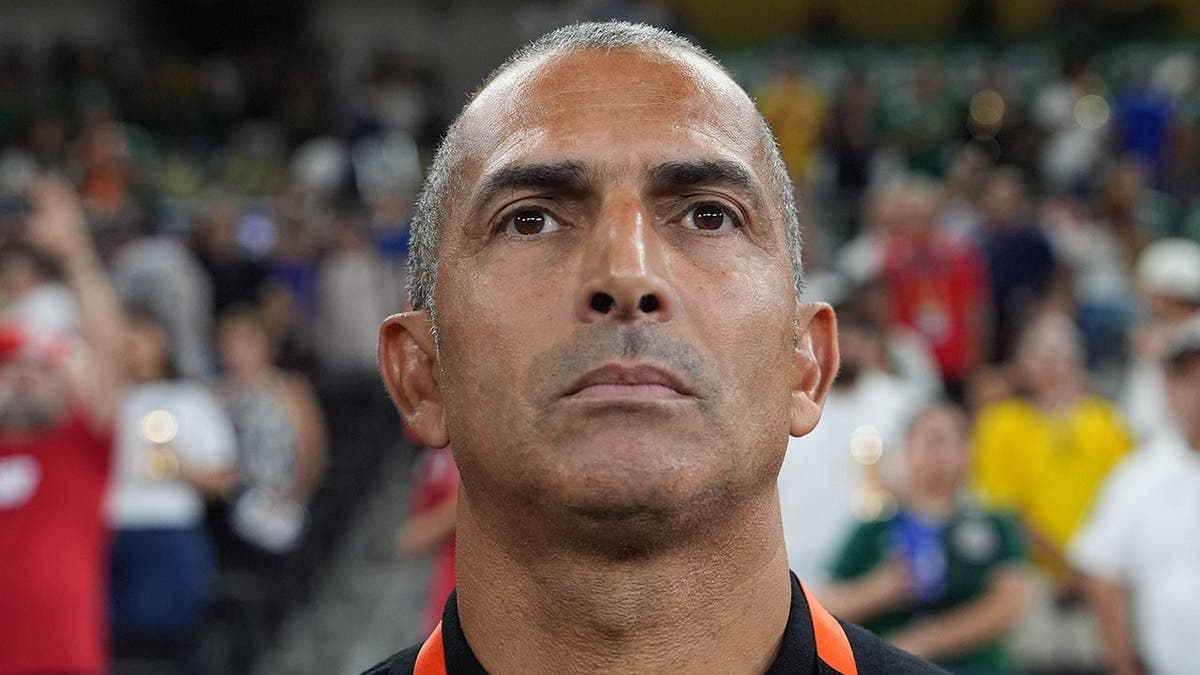 Tunisia head coach Sabri Lamouchi standing on the sideline during a soccer match.