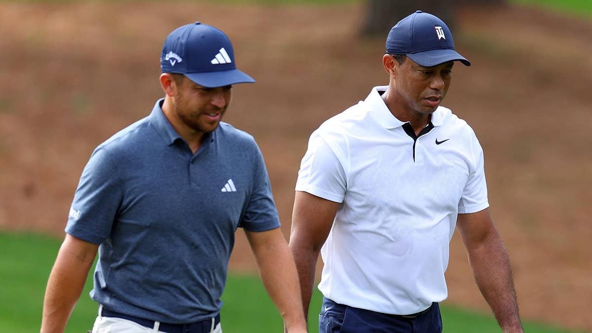 Xander Schauffele and Tiger Woods walking up the third fairway at Augusta National Golf Club.