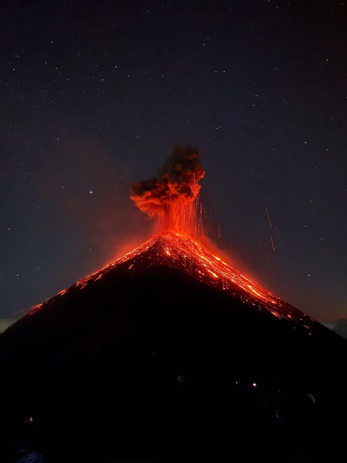 A volcano erupts at night.