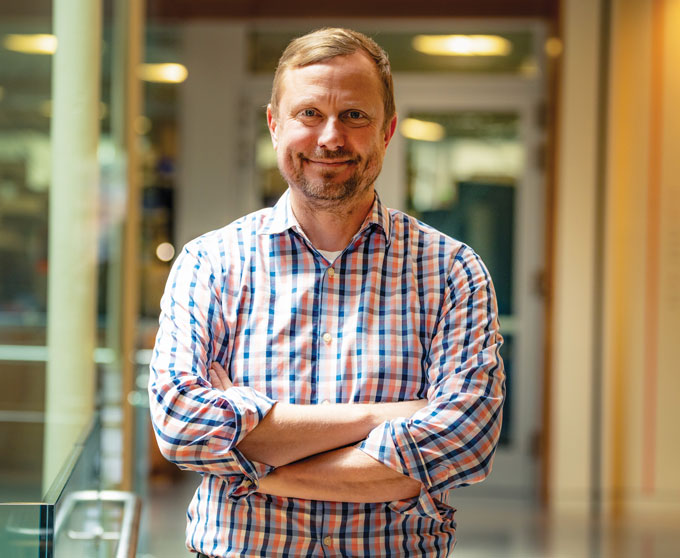 A portrait of Jeff Carroll, standing with his arms crossed. 