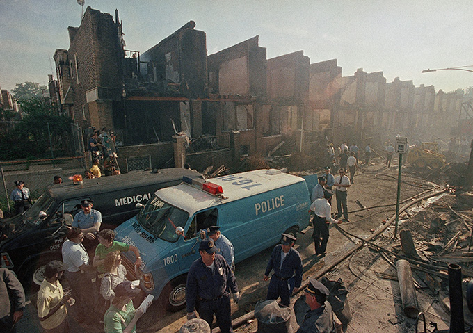 An emergency vehicle parked in front of buildings that show evidence of destruction.