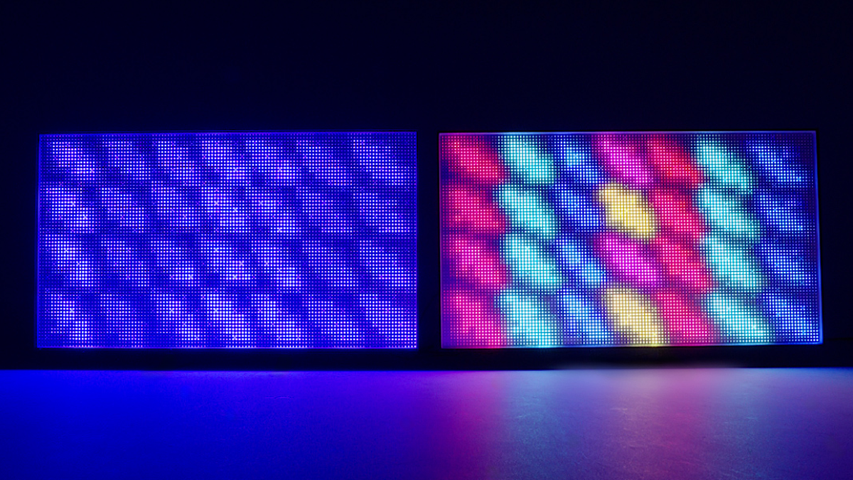 Two TVs side by side, both with only their backlights visible. One is blue-only, the other is True RGB.