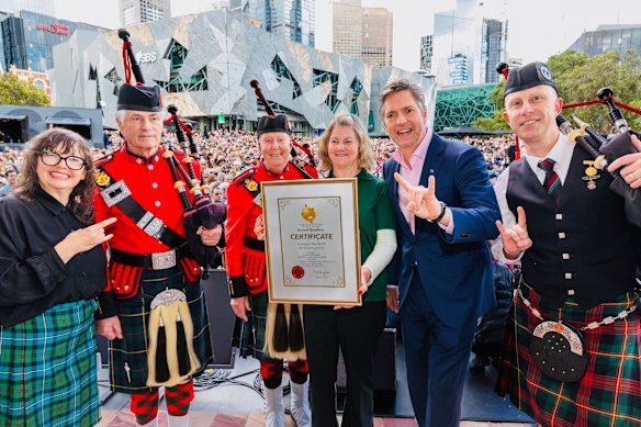 Adjudicator Helen Taylor at Federation Square on November 12, 2025, holding the record certificate for world’s largest bagpipe ensemble. Right of her is Melbourne Lord Mayor Nick Reece.