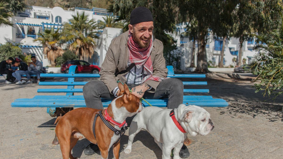 Fergie Chambers walks his dogs on a street in Tunis.