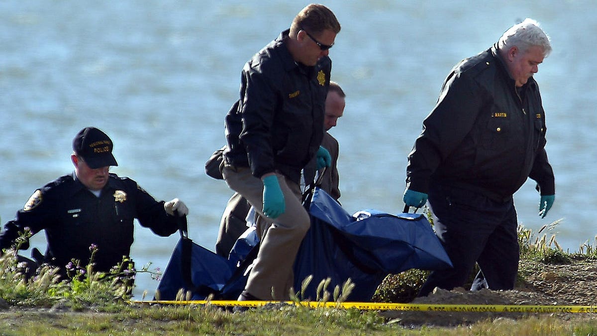 Law enforcement officials remove skeletal remains at Point Isabel.