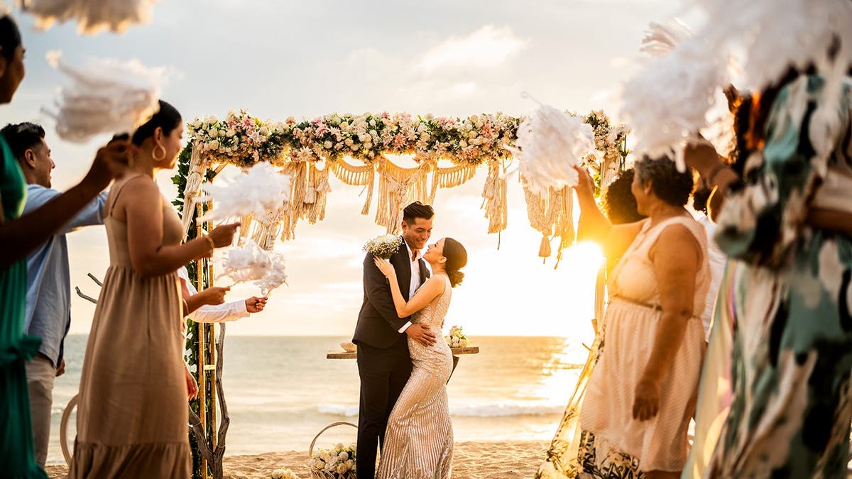 A couple embraces during a beach wedding.