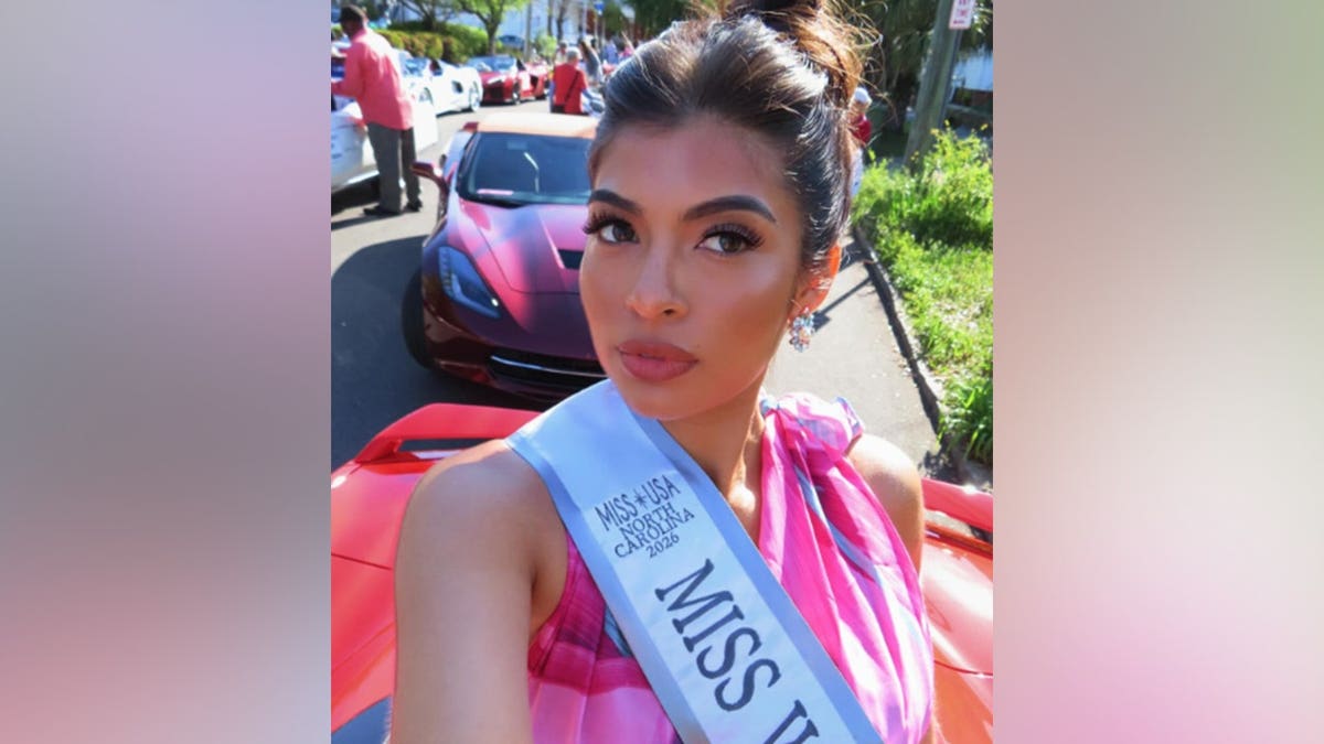 Brittany Boltinhouse wearing a pink dress and Miss Wilmington, USA sash in front of a red sports car