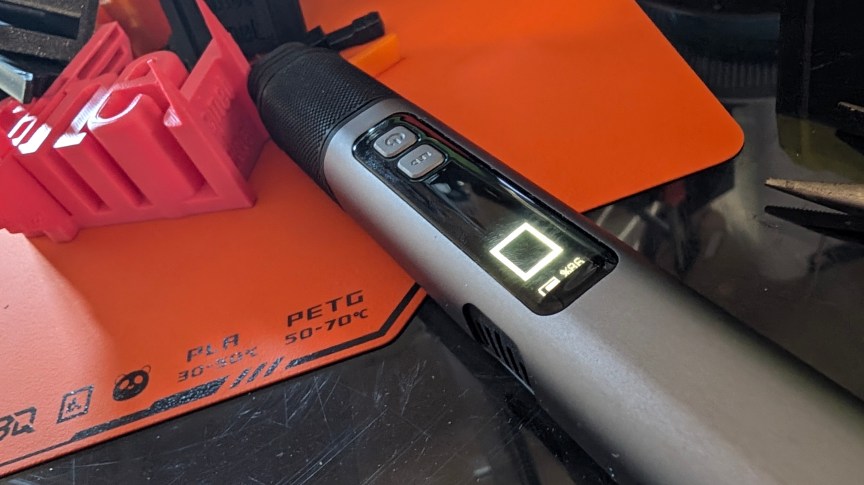 A large gray electric knife on an orange 3D build plate