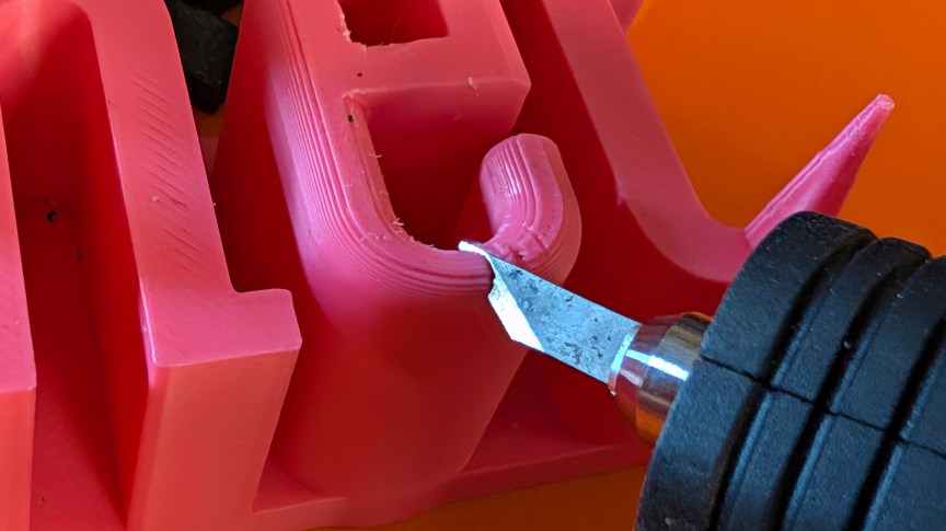 A close-up of a sharp blade cutting through pink plastic