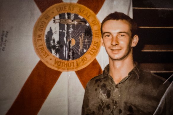 On active duty: Moore posing in Vietnam with a Florida flag belonging to US soldiers.