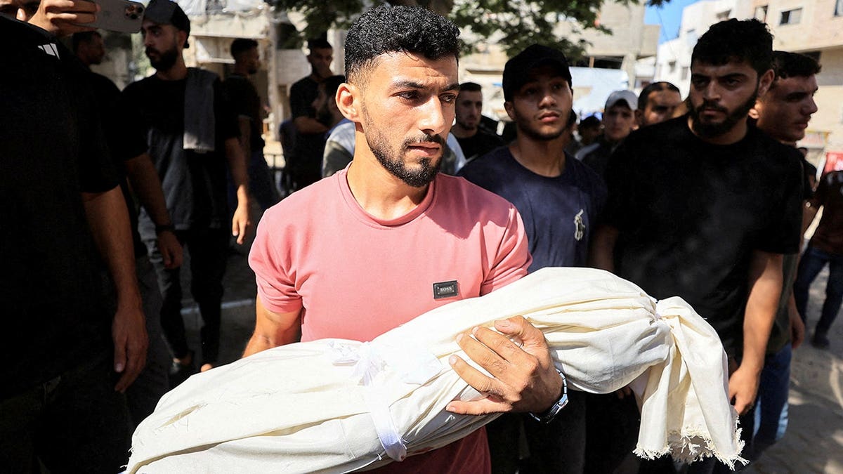 A mourner carries the body of a Palestinian who was killed in Israeli strikes, according to medics, during a funeral, in Gaza City