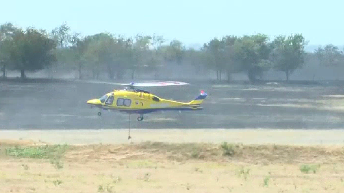 A helicopter responds to the wildfire sparked by a deadly military helicopter crash near Salado, Texas