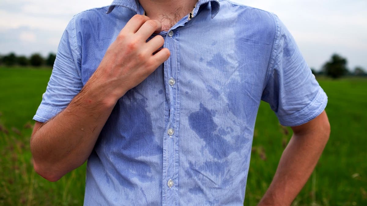 A man stands in a sweaty shirt.
