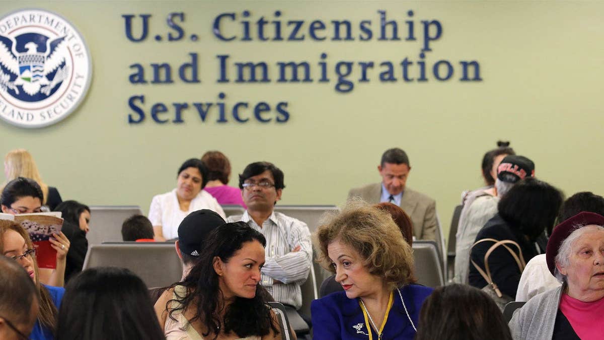 People wait inside a USCIS office as the agency changes its asylum adjudication process