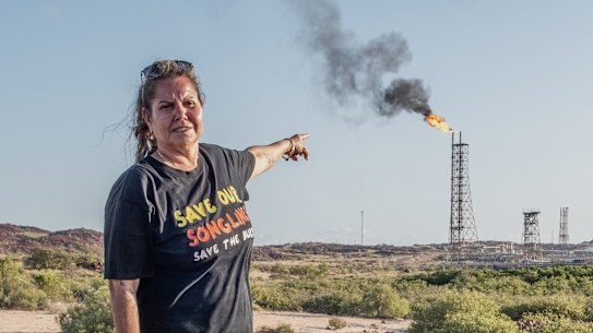 Traditional custodian Raelene Cooper on the Burrup Peninsula, with the Woodside gas plan behind her.