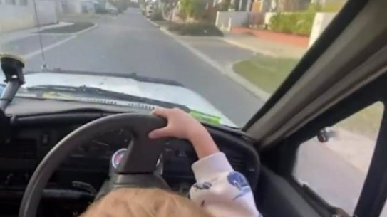 The toddler can be seen sitting on the man’s lap while he steers the car. 