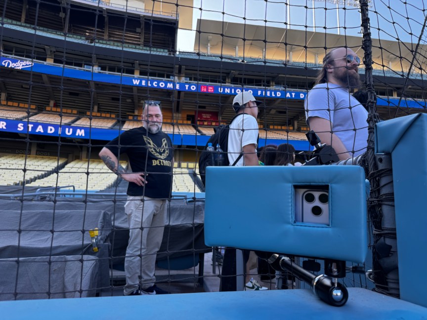 An iPhone 18 Pro Max slid into protective padding in front of netting protecting stadium attendee seats.