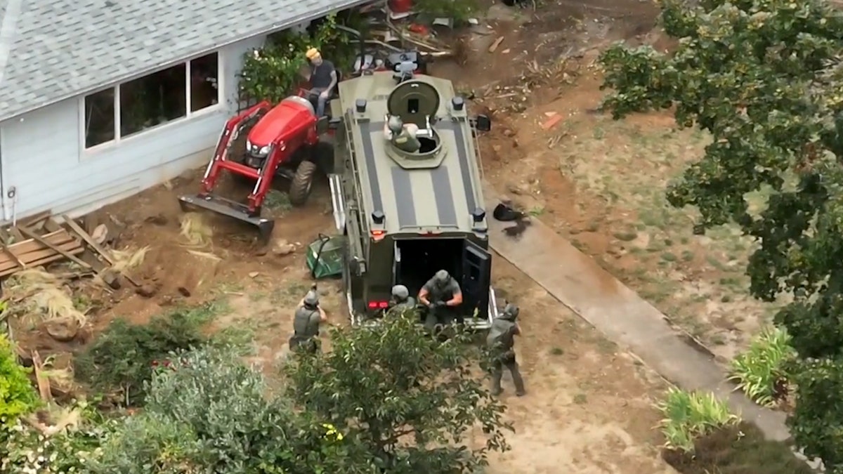 SWAT vehicle pins a suspect's tractor